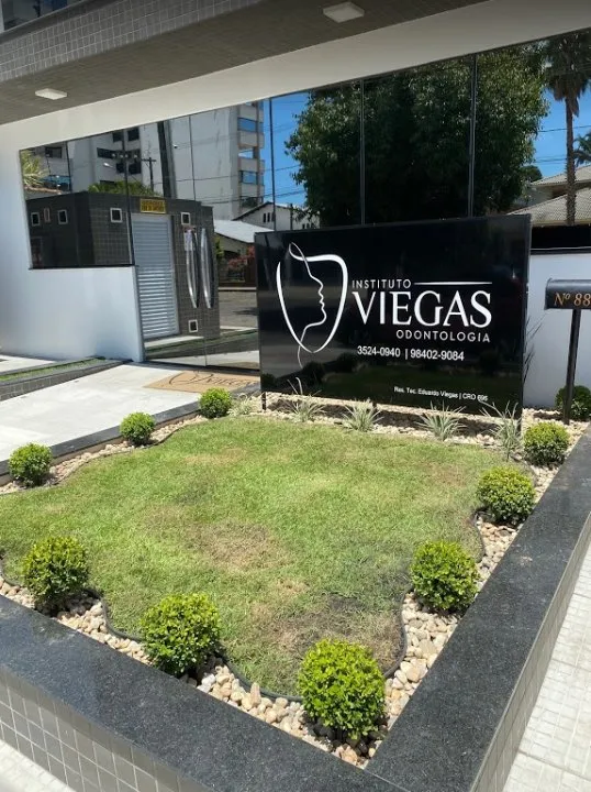 Entrada do Instituto Viegas: placa de granito preto e jardim com buxinhos